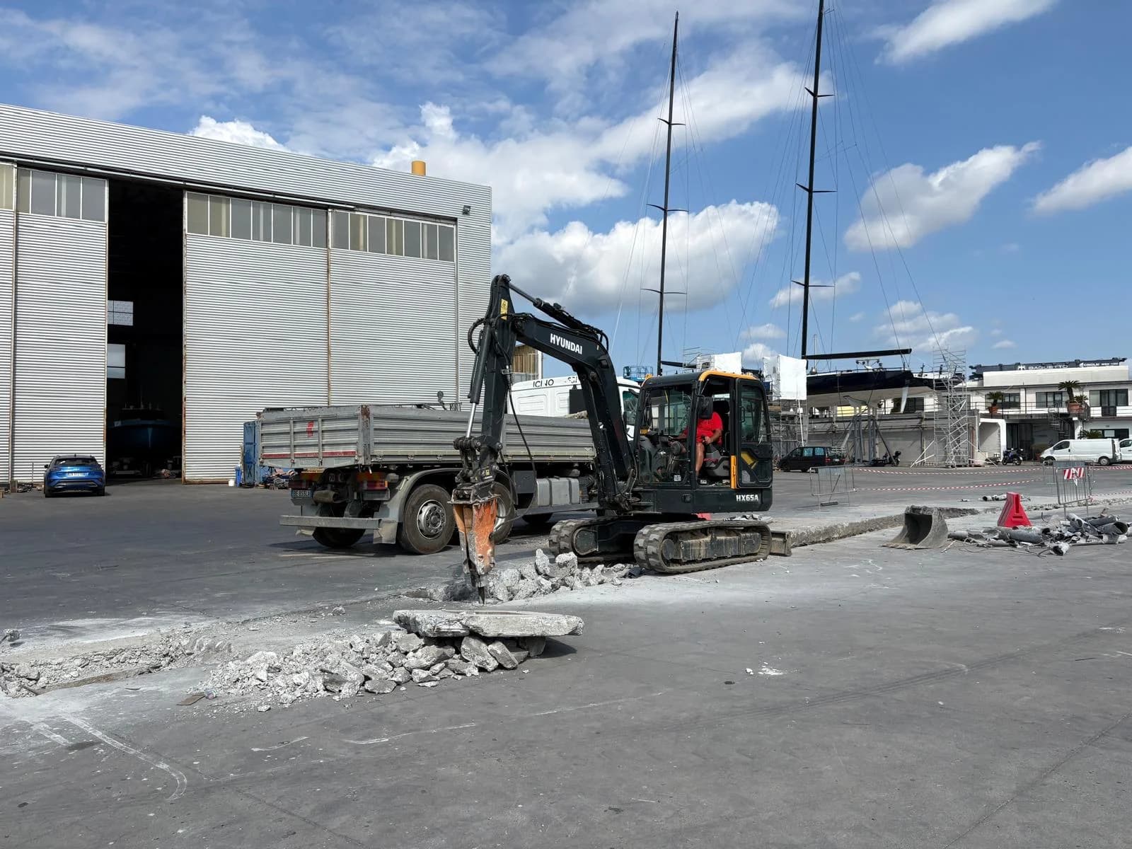 Escavatore con martello demolitore sulla pavimentazione dei Cantieri Navali di La Spezia